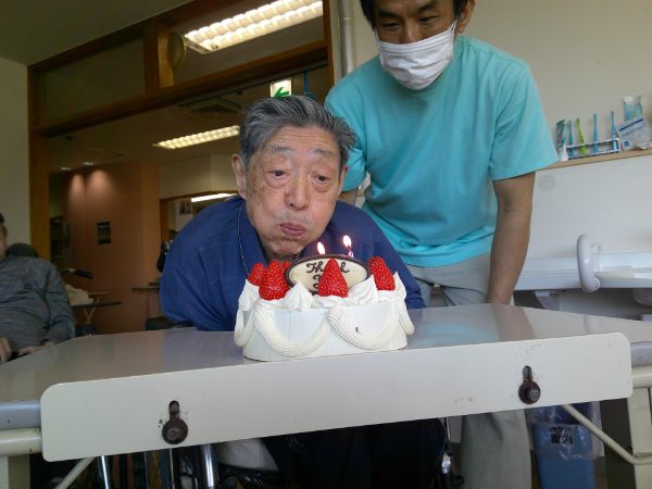 誕生日ケーキの蝋燭の火を消そうとしているお客様