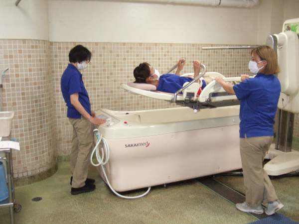 体験する職員が機械浴のストレッチャーに横になり、介助役の職員が操作をしてストレッチャーをあげているところです