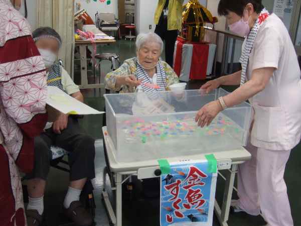 お客様がポイを持って金魚すくいをしているところ