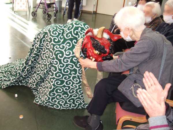 獅子舞がお客様に近づきおひねりを貰っているところる