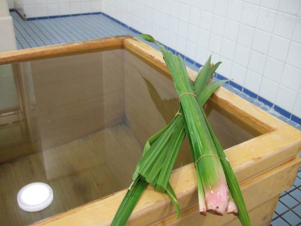 一般浴室のひのき風呂に並々と入っているお湯と菖蒲